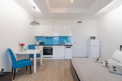 a white kitchen with a table and a blue chair at Bright Studio, 10min Centre, Free Parking in Prague
