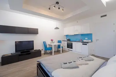 a bedroom with a bed and a kitchen with a tv at Bright Studio, 10min Centre, Free Parking in Prague