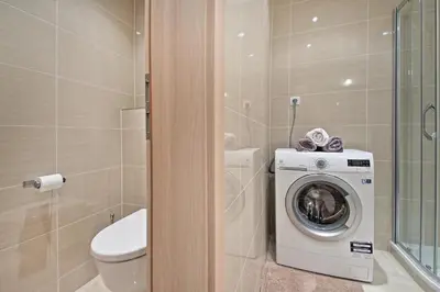 a bathroom with a toilet and a sink and a washing machine at OL apartments in Prague