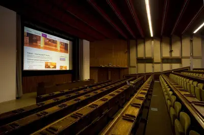 an empty lecture hall with a projection screen and chairs at Hotel Krystal in Prague