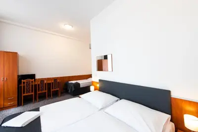a bedroom with two beds and a table and chairs at Hotel Zlatá Váha in Prague