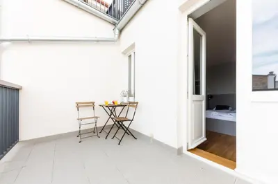 a white apartment with a balcony and a table at Prague Days - Sunny Riverside Apartments with Terraces in Prague