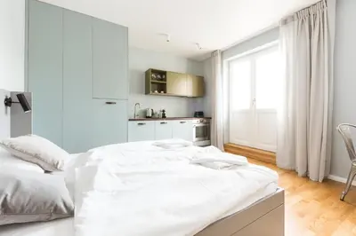 a white bedroom with a large bed and a window at Prague Days - Sunny Riverside Apartments with Terraces in Prague