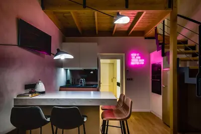 a kitchen with pink walls and a counter with chairs at Prague Days - Sunny Riverside Apartments with Terraces in Prague