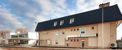 a building with a black roof on a street at Hotel NED HOCKEY in Nymburk