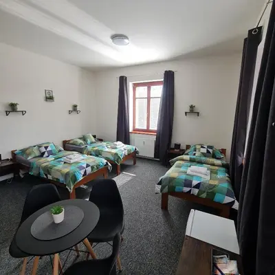 a room with two beds and a table and chairs at Penzion a Restaurace Simanda in Prague