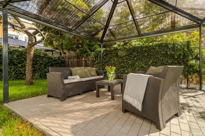 a patio with two chairs and a couch under a pergola at APT with sunny garden Prague by Michal&Friends in Prague