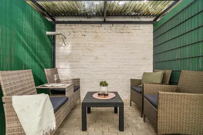 a patio with wicker chairs and a table and a green wall at APT with sunny garden Prague by Michal&Friends in Prague