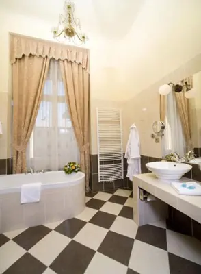 a bathroom with a checkered floor and a tub and sink at Chateau Zbiroh in Zbiroh