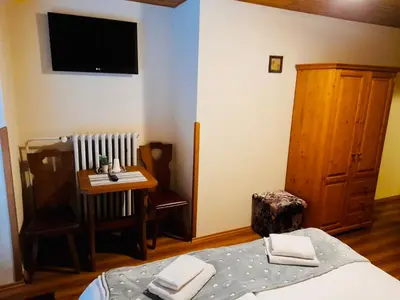 a bedroom with a bed and a table and a television at Restaurant a penzion Pod Draci skalou in Karlštejn