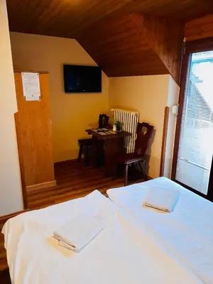 a bedroom with a bed and a table and a television at Restaurant a penzion Pod Draci skalou in Karlštejn