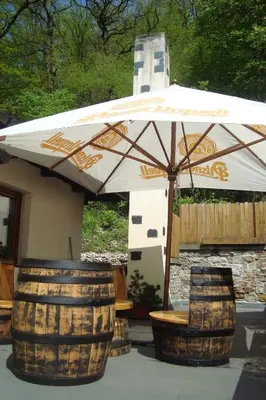 a white umbrella and two barrels and a bench at Restaurant a penzion Pod Draci skalou in Karlštejn