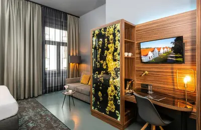 a hotel room with a desk and a bedroom at NYX Hotel Prague by Leonardo Hotels in Prague