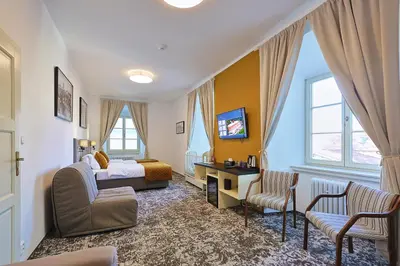 a bedroom with a bed and a desk and chairs at Hotel Tynec in Týnec nad Sázavou