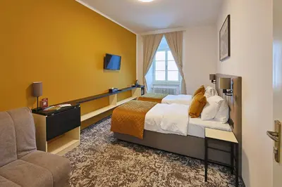 a hotel room with a bed and a chair at Hotel Tynec in Týnec nad Sázavou