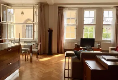 a living room with a table and a kitchen with windows at Spacious elegance in the heart of Old Town in Prague