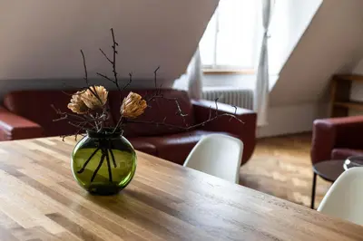 a green vase with flowers on a wooden table at Bright stylish central apartments Prague in Prague