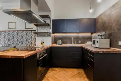 a kitchen with black cabinets and wooden counter tops at Prague Trendy Central Apartment by Michal&Friends in Prague