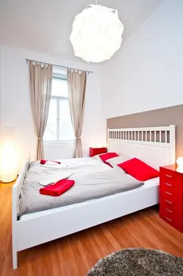 a bedroom with a large white bed with red pillows at Budget Apartment in Prague