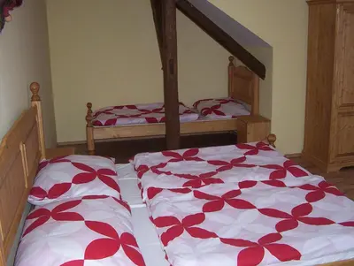 a bedroom with two beds with red and white blankets at Penzion U červených vrat in Chudolazy