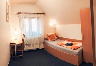 a small room with a bed with a window at Penzion V Maštali in Kněževes