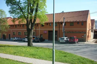 a building with cars parked in a parking lot at Penzion V Maštali in Kněževes