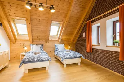 two beds in a room with wooden walls at Vinný apartmán Rakovník in Rakovník