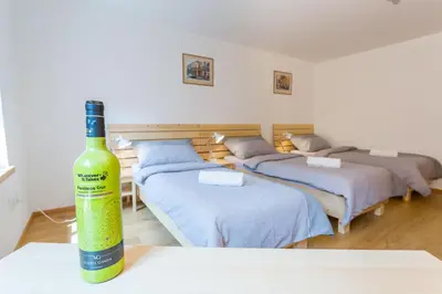 a bottle of wine sitting on a table with three beds at Vinný apartmán Rakovník in Rakovník