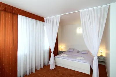 a bedroom with a bed with white curtains at Hotel Pod Sluncem in Třebíz