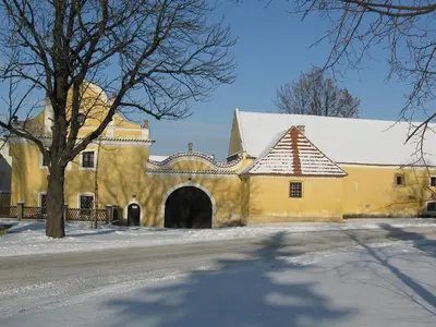 a yellow building with a gate in the snow at Hotel Pod Sluncem in Třebíz