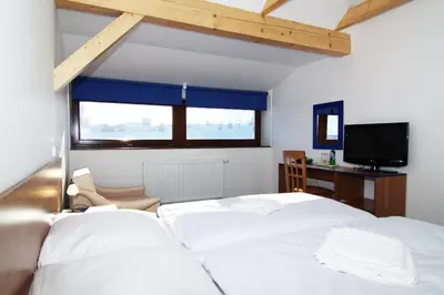 a bedroom with a white bed and a television at Hotel Pod Sluncem in Třebíz