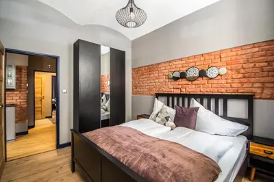 a bedroom with a large bed with a brick wall at 3BDR RUTERRA Apt with Table Football in Prague