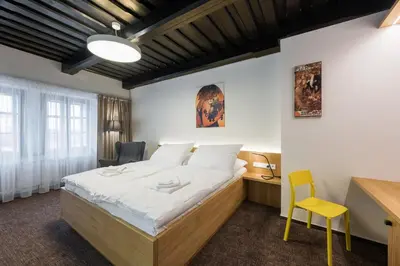 a bedroom with a bed and a desk and a yellow chair at Fancy apartments by Prague Castle in Prague