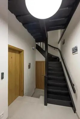 a hallway with a staircase with a large light overhead at Fancy apartments by Prague Castle in Prague