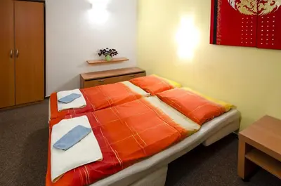 a bedroom with a bed with an orange comforter at Hotel Imos in Prague