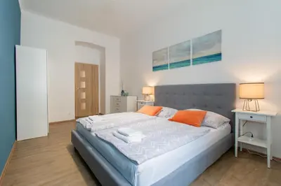 a bedroom with a large bed with orange pillows at Stay Inn Apartments Naplavka in Prague