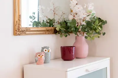 a table with two vases and a mirror and flowers at Stay Inn Apartments Naplavka in Prague
