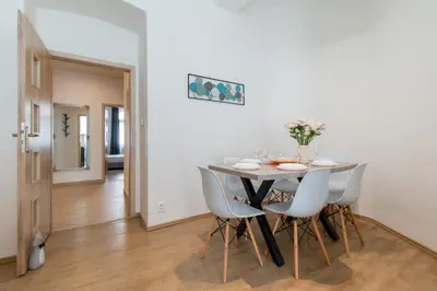 a white dining room with a table and chairs at Stay Inn Apartments Naplavka in Prague
