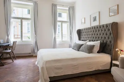 a bedroom with a large bed and two windows at Kent Ridge Loft (Lublanska) in Prague