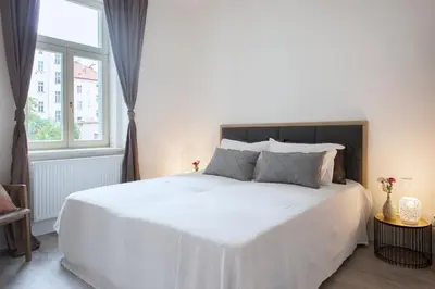 a bedroom with a large white bed with a window at Kent Ridge Loft (Lublanska) in Prague