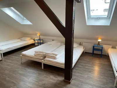 a attic room with two beds and two windows at Clown and Bard Hostel in Prague