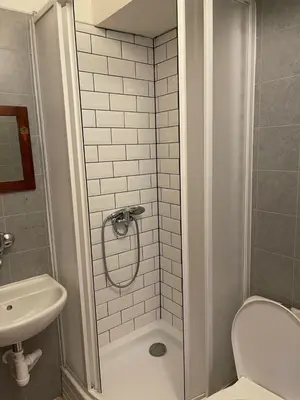 a bathroom with a shower and a toilet and a sink at Clown and Bard Hostel in Prague