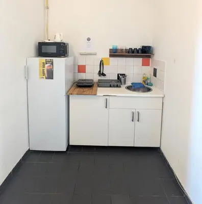 a kitchen with white cabinets and a refrigerator at Clown and Bard Hostel in Prague