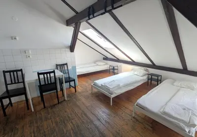 a attic room with two beds and a table and chairs at Clown and Bard Hostel in Prague