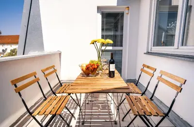 a table and chairs on a balcony with a bottle of wine at HOME ALONE 5BR+3BATH Penthouse in center of Prague in Prague