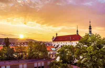 a view of a building with a sunset in the background at HOME ALONE 5BR+3BATH Penthouse in center of Prague in Prague