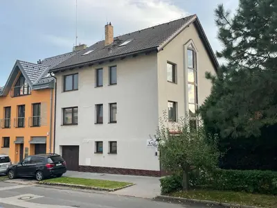 a white house with a car parked in front of it at A.V.E. Pension Kliská in Prague