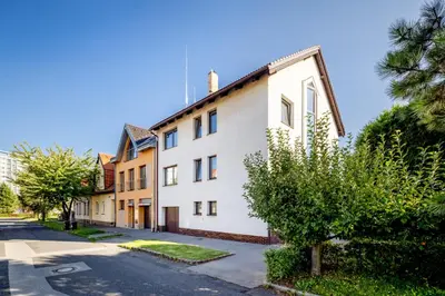 a white building on a street with a tree at A.V.E. Pension Kliská in Prague