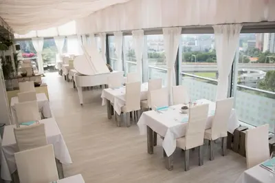 a restaurant with white tables and white chairs and windows at Balu Apartments in Prague