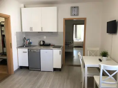 a kitchen with white cabinets and a table and a dining room at Apartment Happy 11 in Prague